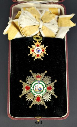 Estuche con la Gran Cruz y Encomienda de Oro de 18K con su Banda de la Orden de Isabel la Católica. Manufactura de "CEJALVO Y GARCIA, MADRID". Circa 1860. Alfonso XII